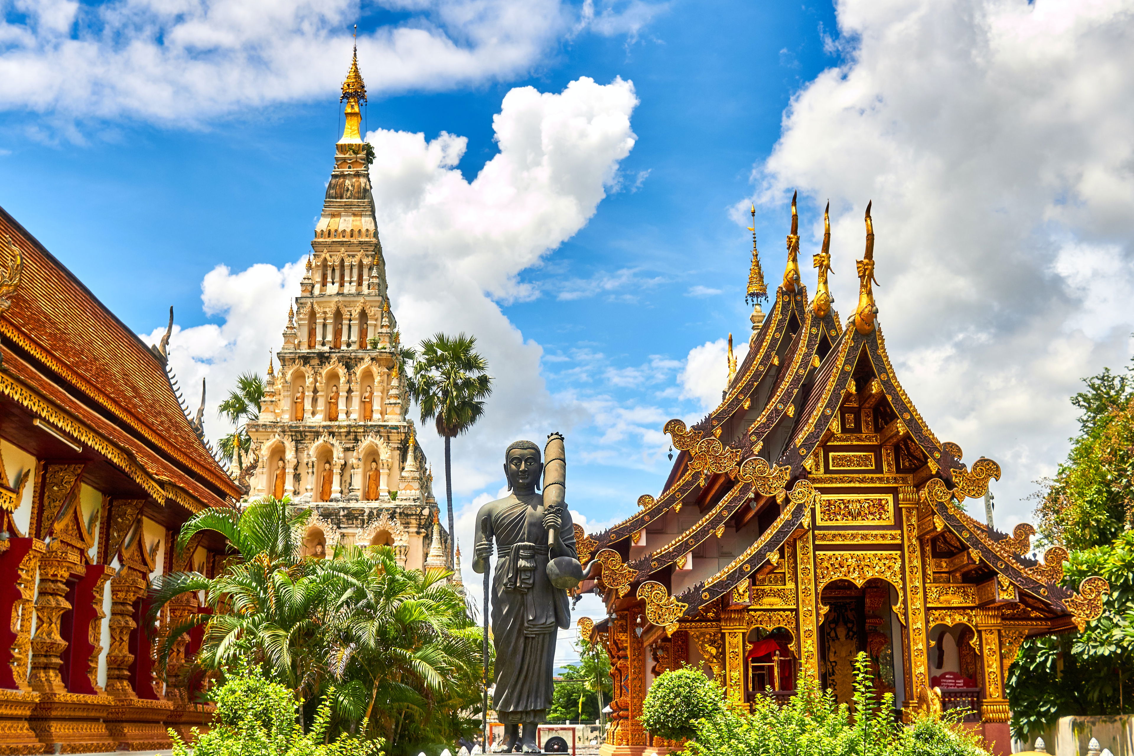 Thailand und die Cannabis-Legalisierung: Zwischen Tradition und Moderne Traditioneller thailändischer Tempel mit goldverzierter Architektur und Buddhastatue unter blauem Himmel – Symbol für Kulturwandel in Thailand.