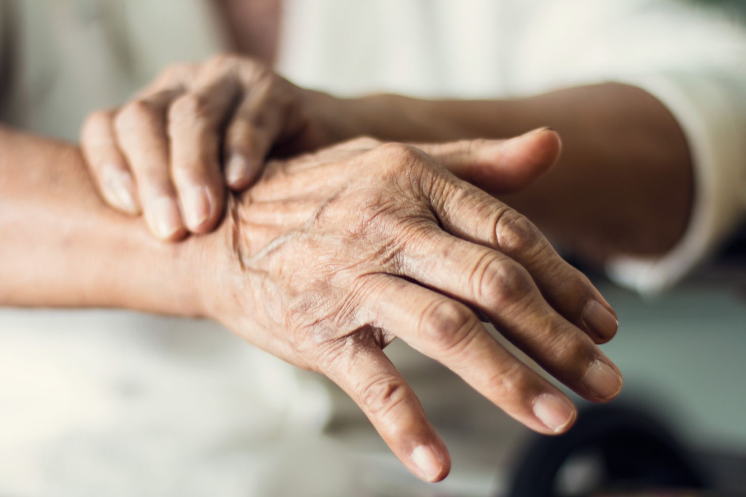 CBD bei Parkinson – Unterstützung für mehr Lebensqualität Nahaufnahme von zwei älteren Händen, die sich gegenseitig halten – sichtbare Anzeichen von Zittern oder Verspannung deuten auf Parkinson-Symptome hin.