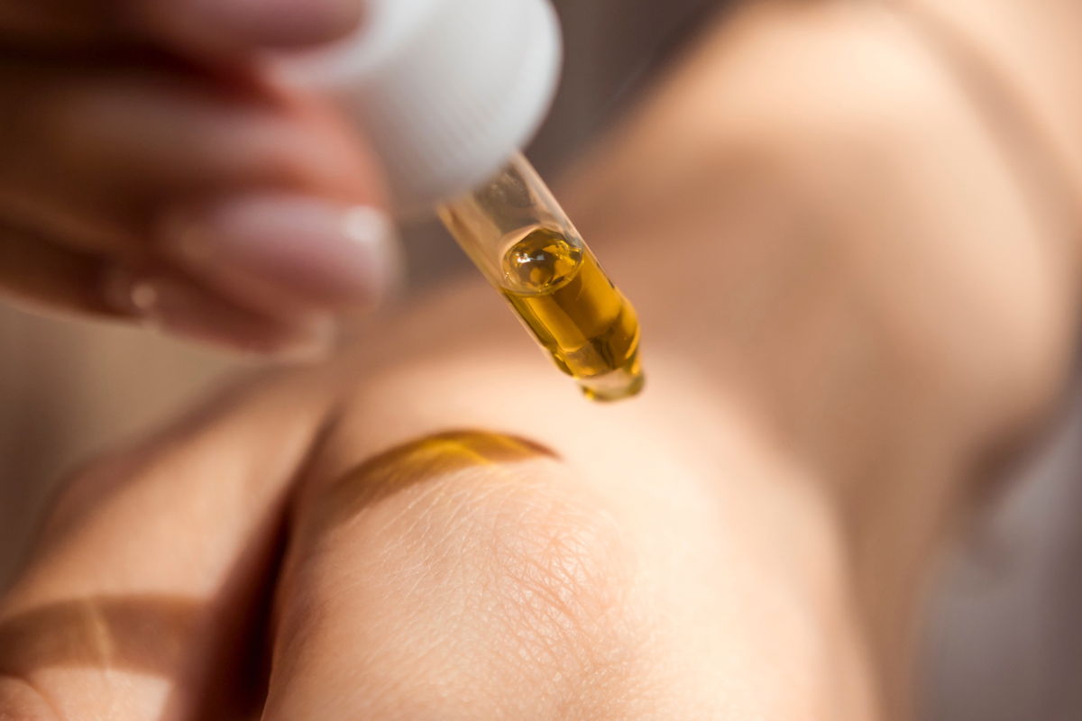CBD bei Hauterkrankungen: Sanfte Pflege aus der Natur Nahaufnahme einer Hand, auf die mit einer Pipette CBD-Öl aufgetragen wird – natürliche Pflege bei Hautproblemen.