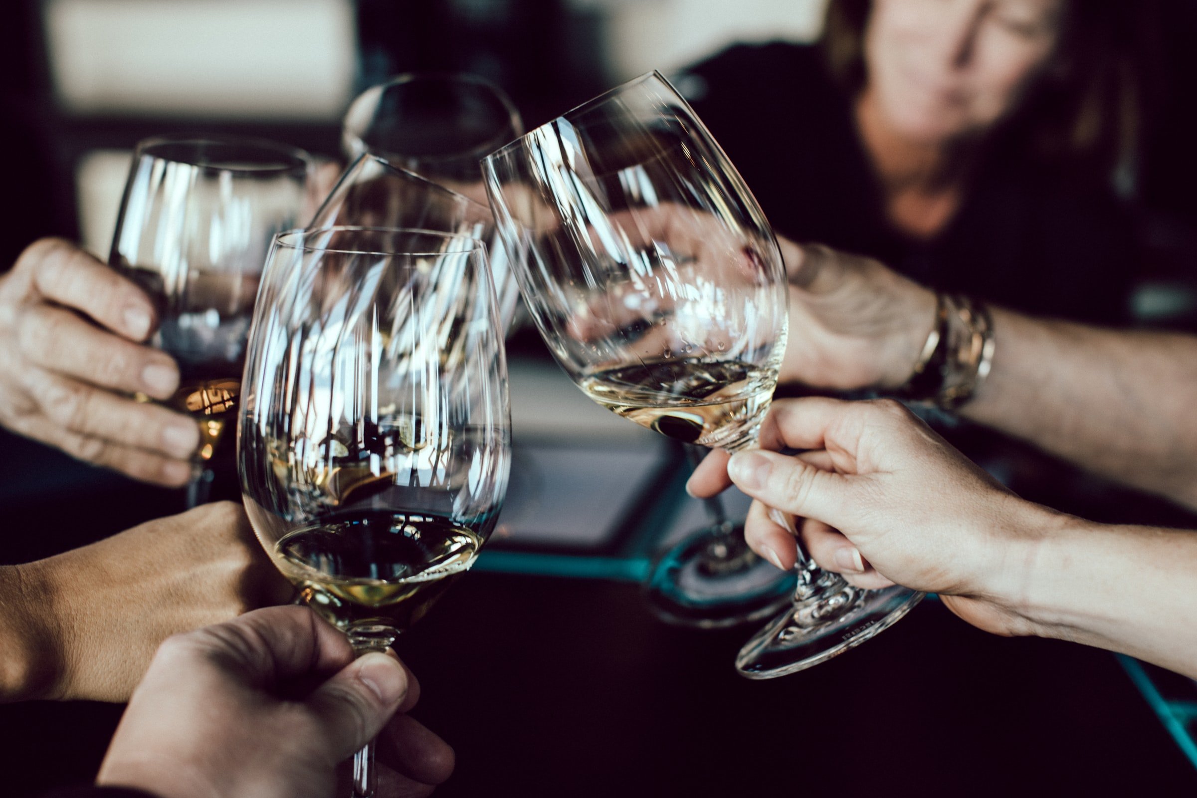 Gruppe von Menschen stößt mit Weingläsern an – symbolisiert Alkoholgenuss, geselliges Beisammensein und potenzielle Wechselwirkungen mit CBD.