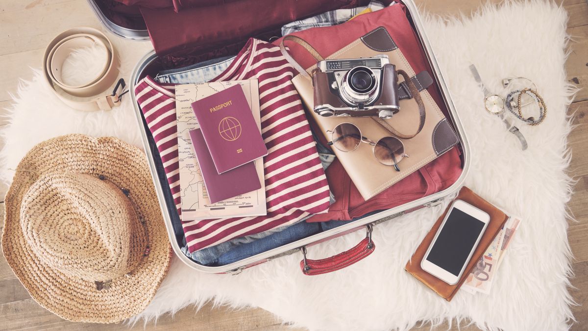 Reisen mit CBD – Was muss ins Gepäck? Offener Koffer mit Kleidung, Reisepass, Kamera und Reiseutensilien – Symbolbild für Reisevorbereitungen mit CBD-Produkten
