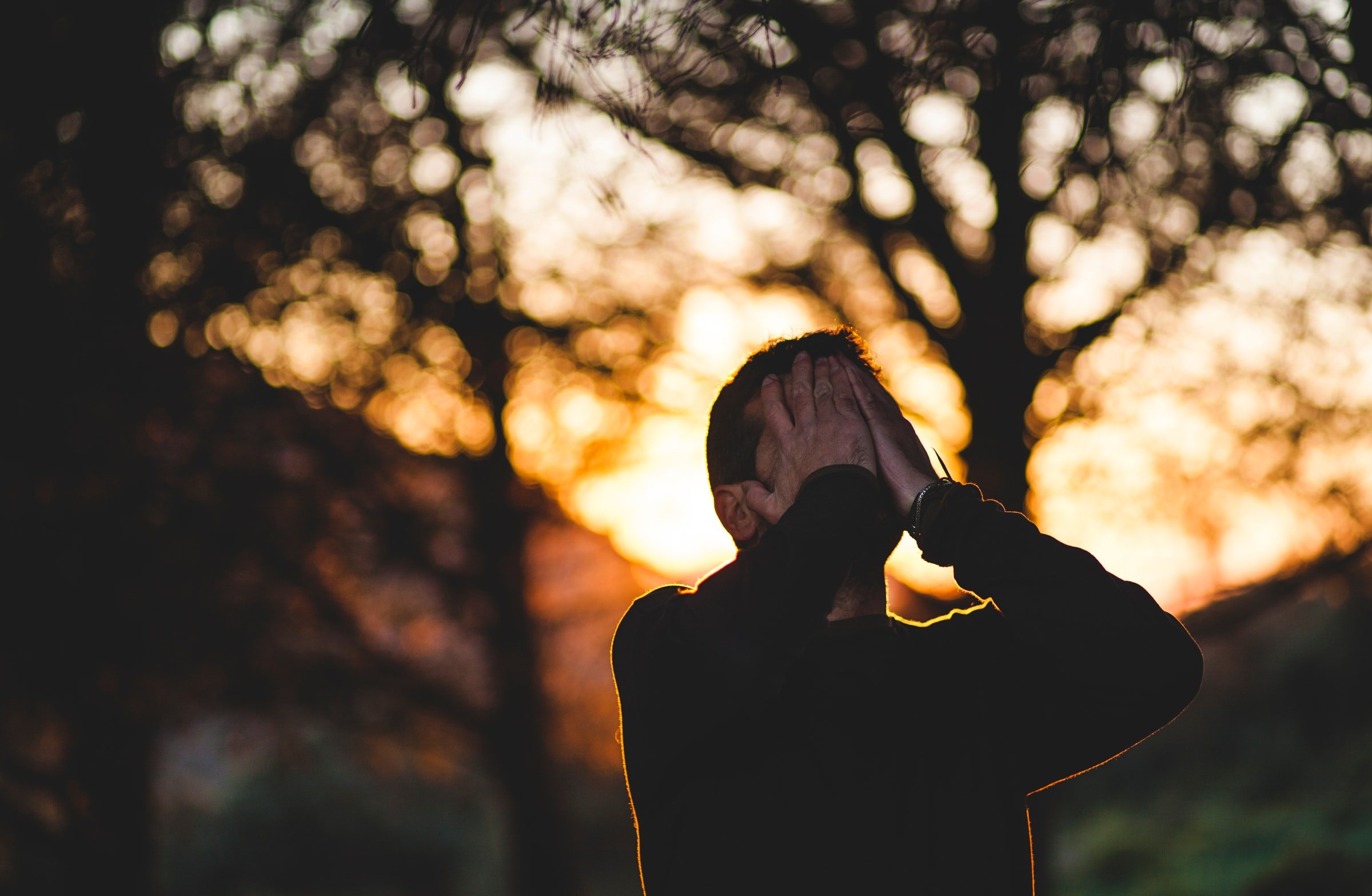 CBD bei Hochsensibilität – Wenn Reize zur Belastung werden Mann mit den Händen im Gesicht im Gegenlicht der Abendsonne – symbolisiert emotionale Überforderung oder Reizüberflutung.