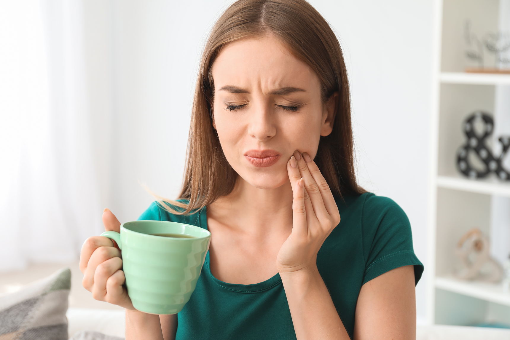 CBD Öl gegen Zahnschmerzen – Natürliche Unterstützung bei Entzündungen und Schmerzreduktion Frau hält schmerzhaft ihre Wange und trinkt Tee – Symbolbild für Zahnschmerzen und die Anwendung von CBD Öl zur Linderung