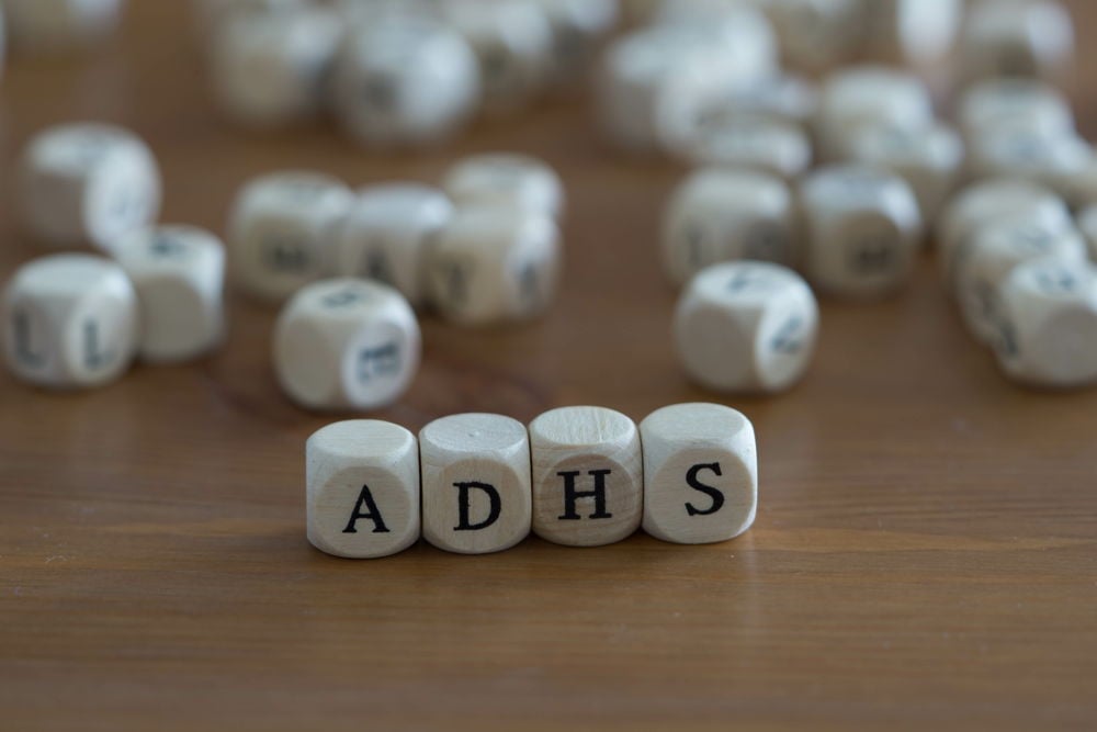CBD bei ADHS – Fokus auf Aufmerksamkeitsdefizit-Hyperaktivitätsstörung Vier Holzbuchstabenwürfel mit der Aufschrift „ADHS“, im Vordergrund scharf fokussiert, umgeben von weiteren unscharfen Würfeln – symbolisch für Unruhe und Konzentrationsprobleme bei ADHS.