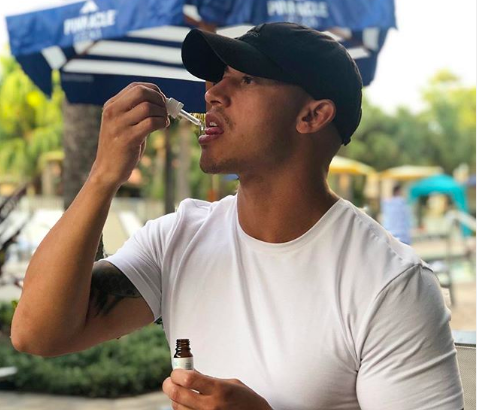 Mann nimmt CBD Öl mit Pipette unter freiem Himmel ein