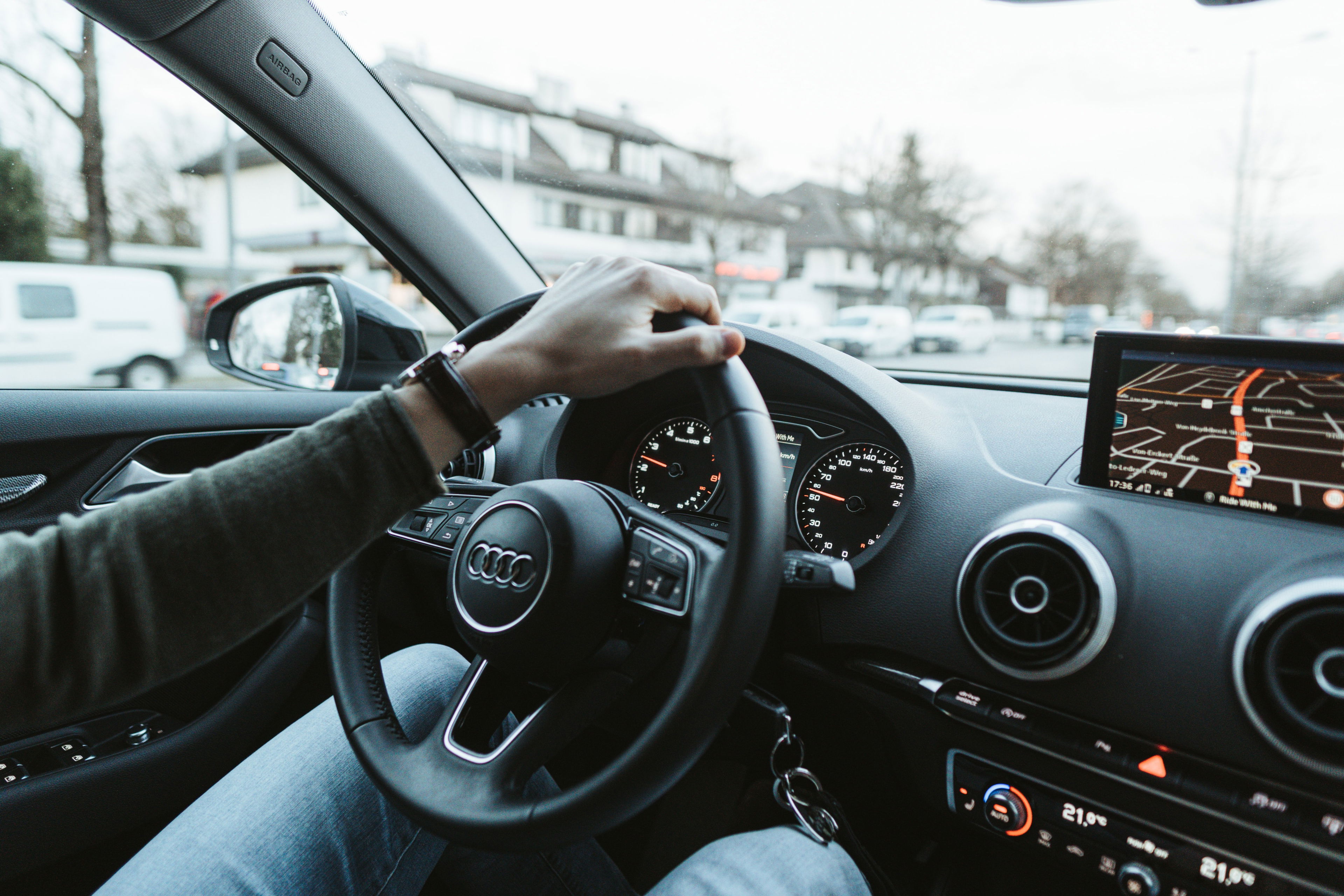 Blick aus dem Fahrzeuginneren: Eine Person hält das Lenkrad eines Audi, Navigationssystem zeigt eine Route – Symbolbild für Autofahren und Verkehrssicherheit. CBD beim Autofahren – sicher unterwegs mit Cannabidiol?