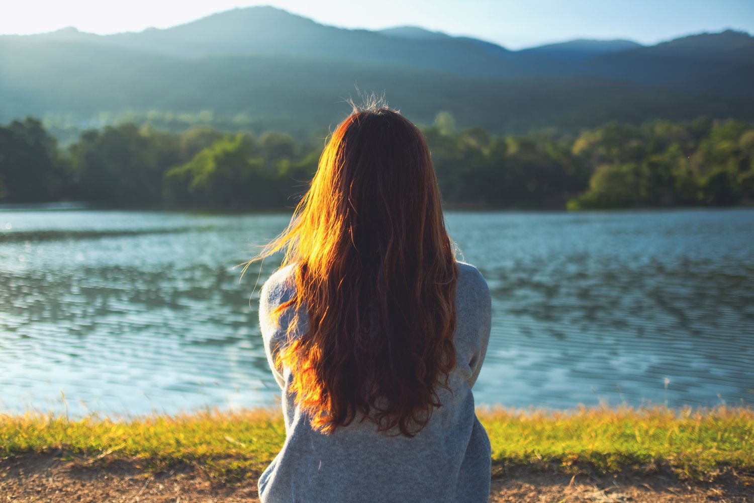 Den Weg zurück finden – CBD als Hilfe bei Suchterkrankungen Frau sitzt nachdenklich am Seeufer und blickt auf das Wasser – Symbolbild für Reflexion und den Ausstieg aus der Sucht mit CBD