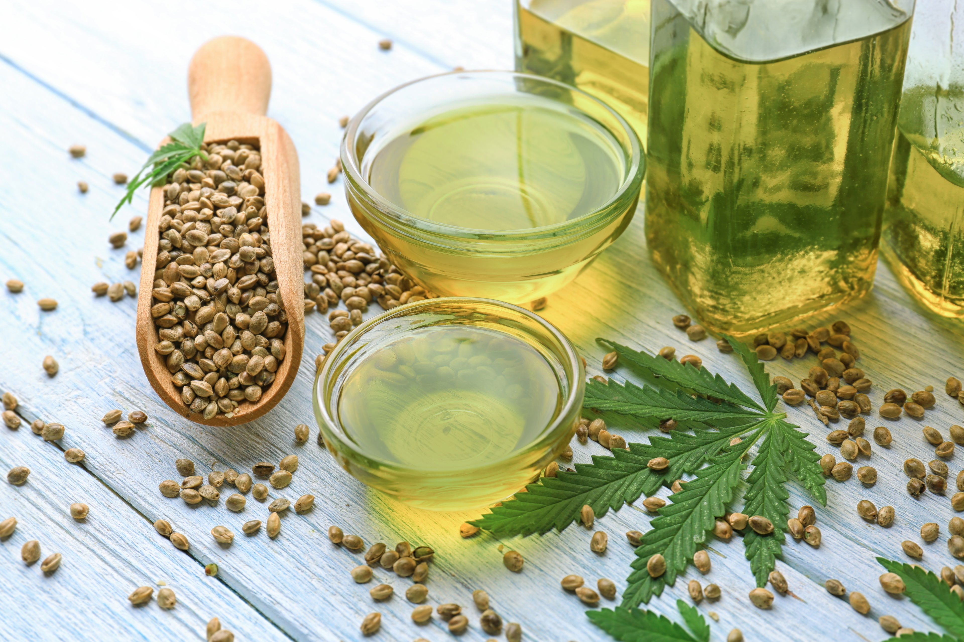 Hanfsamen und Hanföl – Gesunde Kraftpakete aus der Natur Hanfsamen in Holzlöffel und Schälchen mit Hanföl auf hellem Holztisch – Symbolbild für die gesundheitlichen Vorteile von Hanfsamen