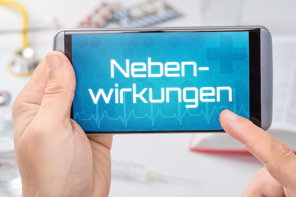 Nebenwirkungen von CBD – worauf sollte man achten? Smartphone mit dem Schriftzug „Nebenwirkungen“ auf dem Display, im Hintergrund medizinische Utensilien – Symbolbild für mögliche Nebenwirkungen von CBD
