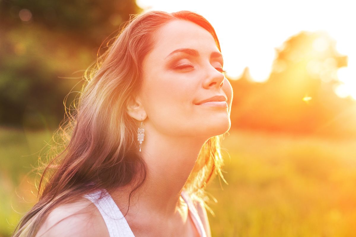 Positive Erfahrungen mit CBD-Öl – Gelassenheit und Wohlbefinden Junge Frau genießt entspannt die Sonne auf einem Feld – Symbol für innere Ruhe durch CBD-Öl-Erfahrungen