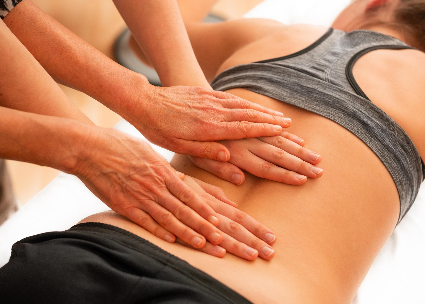 Linderung bei Rückenschmerzen – gezielte Entspannung mit CBD und Massage Person in Sportkleidung liegt auf dem Bauch und erhält eine Massage im unteren Rückenbereich – Anwendung bei Rückenschmerzen